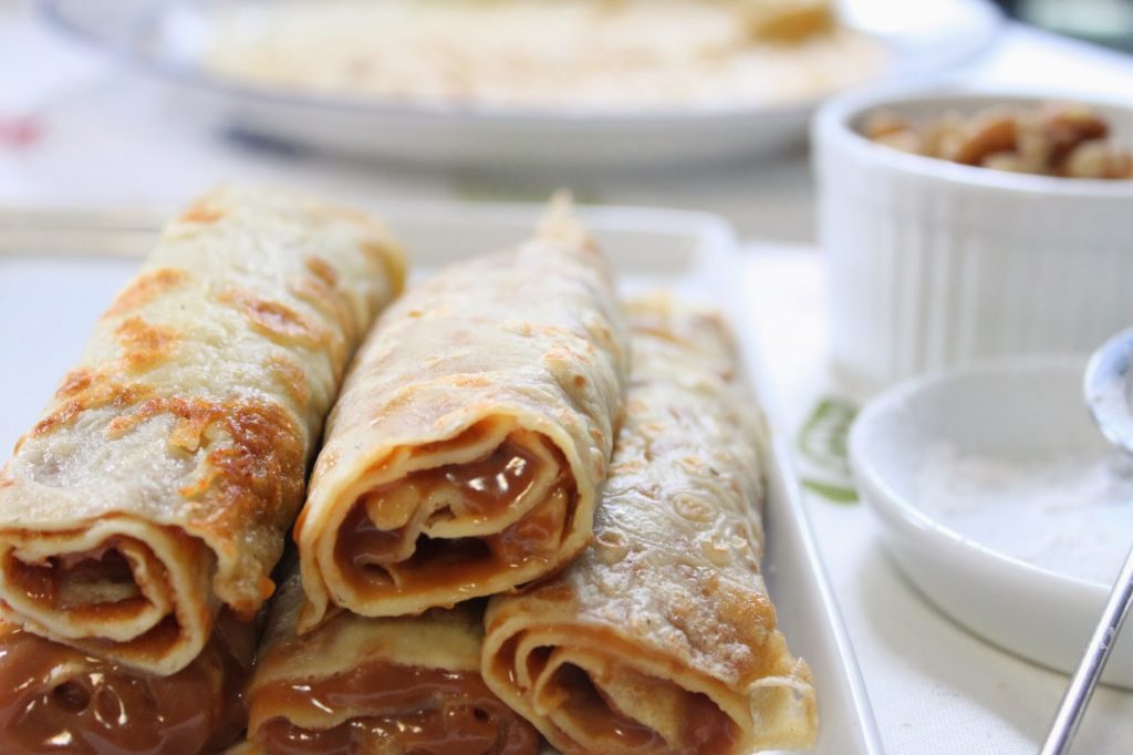 Puedes hacer panqueques con dulce de leche o nutella. Rollos de panqueques finos rellenos de dulce de leche en plato blanco