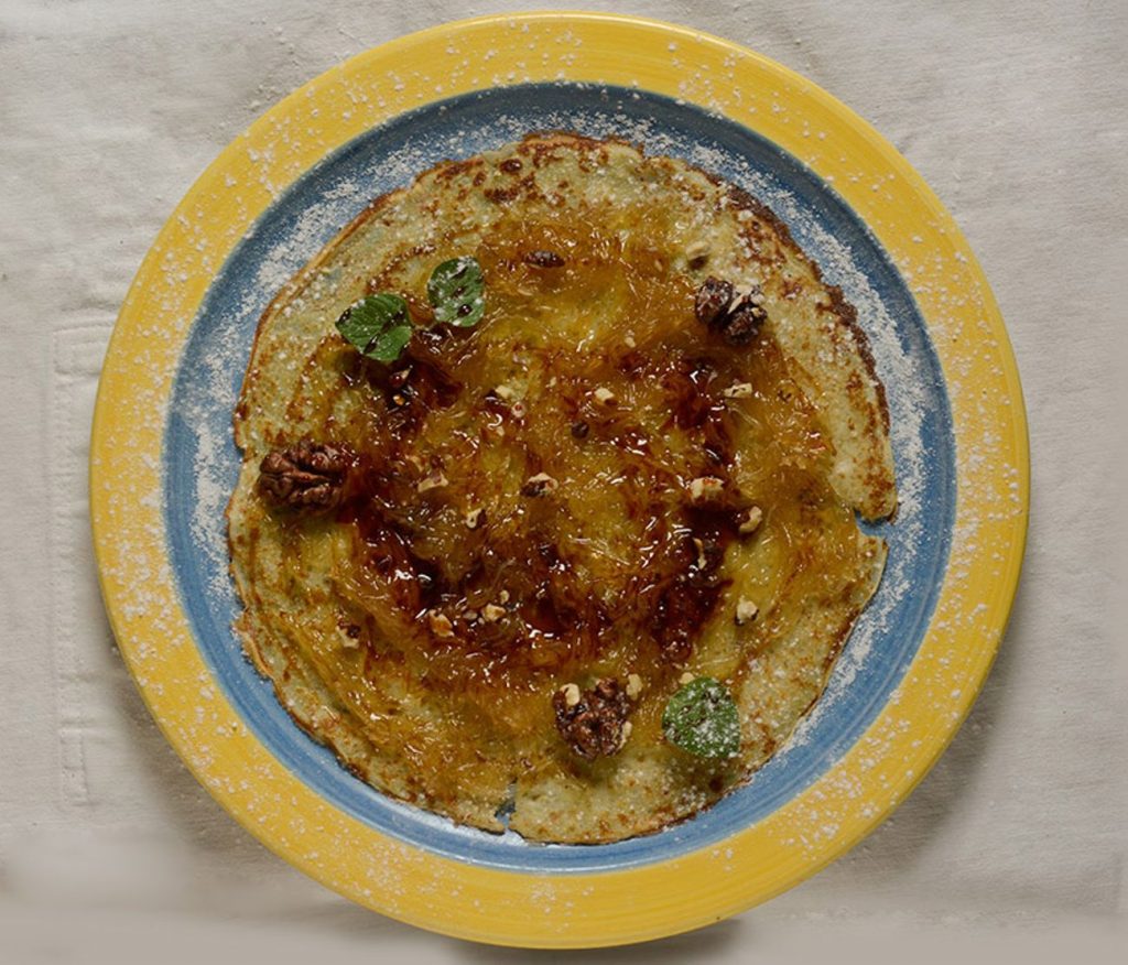 Ideas de Recetas con Quinoa Ejemplo de receta saludable con quinoa: un pancake cubierto con miel y nueces en un plato.