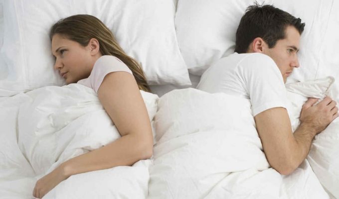 Mujer y hombre pensativos, acostados en la cama, simbolizando falta de deseo sexual