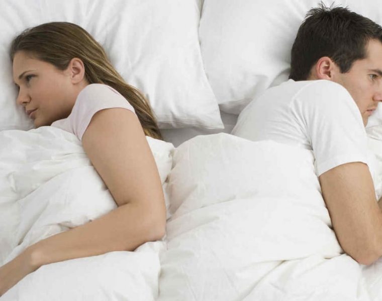 Mujer y hombre pensativos, acostados en la cama, simbolizando falta de deseo sexual