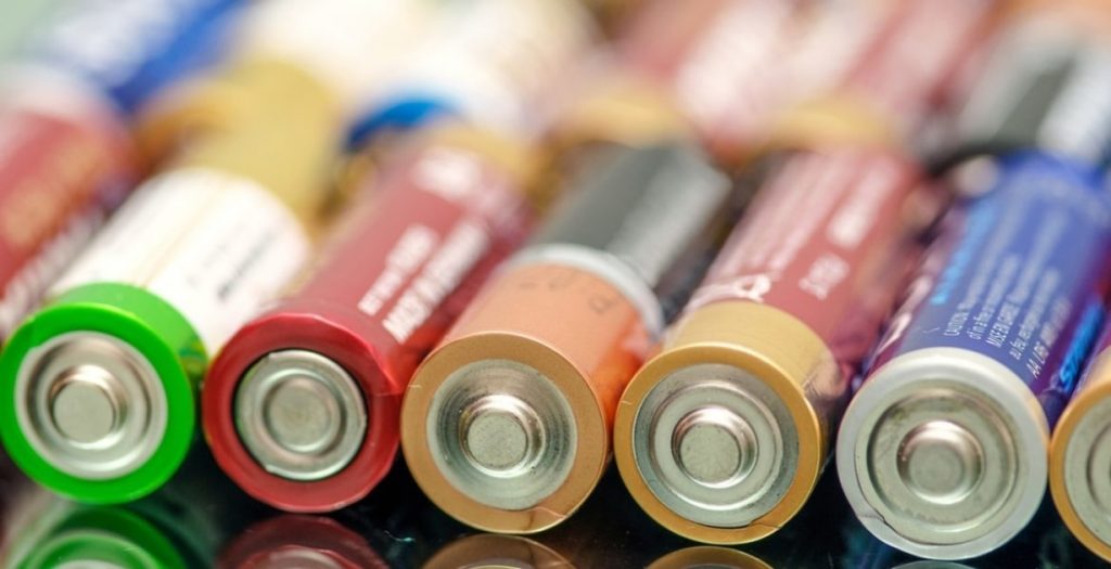 Varias pilas alcalinas de distintos colores colocadas una al lado de la otra, enfocando la parte del polo positivo.