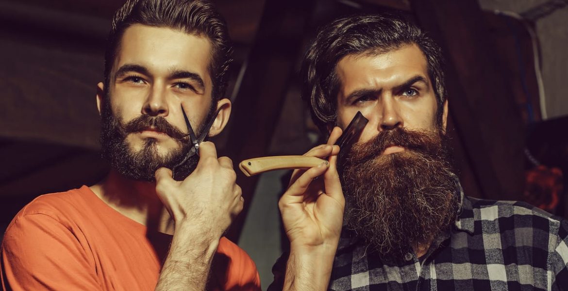 Hombre usando máquina para recortar su barba frente al espejo