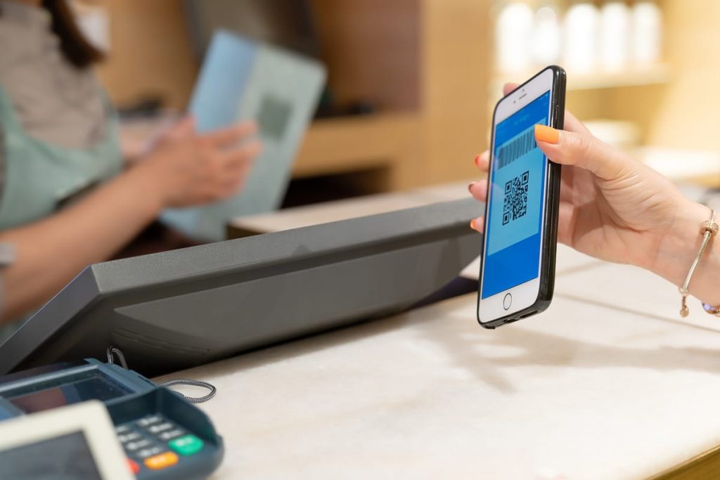 mujer mostrando su teléfono con una app de reintegro al pagar