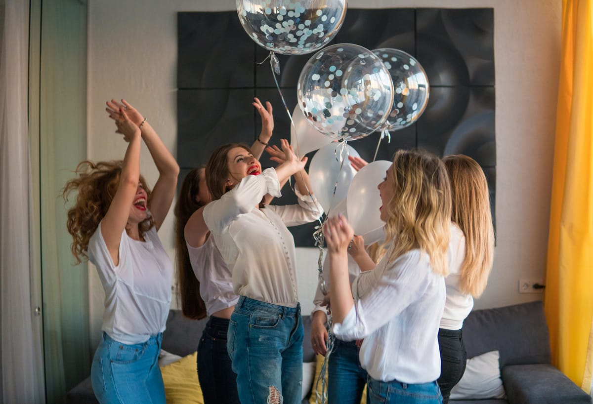 Estudiantes celebrando en fiesta universitaria con globos y ropa moderna
