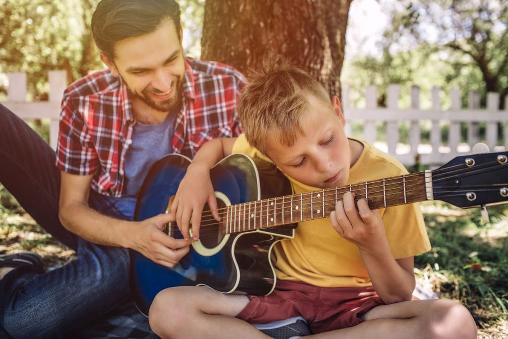 niño aprendiendo a tocar la guitarra con su padre como aprender a tocar guitarra facil