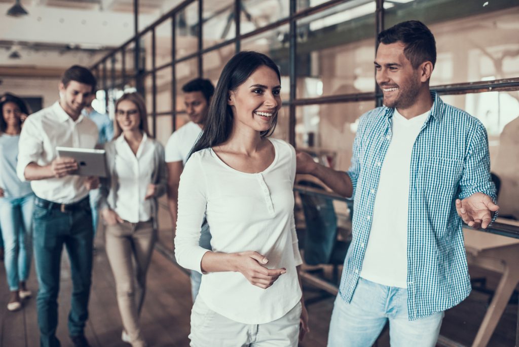 El Éxito Profesional como Nueva Prioridad Grupo de jóvenes profesionales sonriendo en la oficina, representando cómo la carrera y la vida social en el trabajo son una prioridad para las nuevas generaciones.