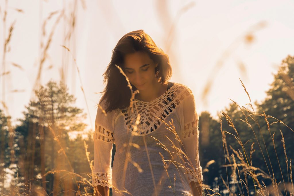 Mujer vestida de blanco caminando entre hierbas altas al atardecer, simbolizando calma, energía espiritual y nuevos comienzos en septiembre