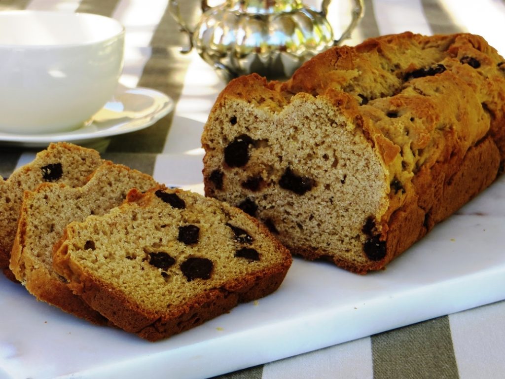 Budín casero con pasas, servido en rodajas sobre una tabla de mármol.