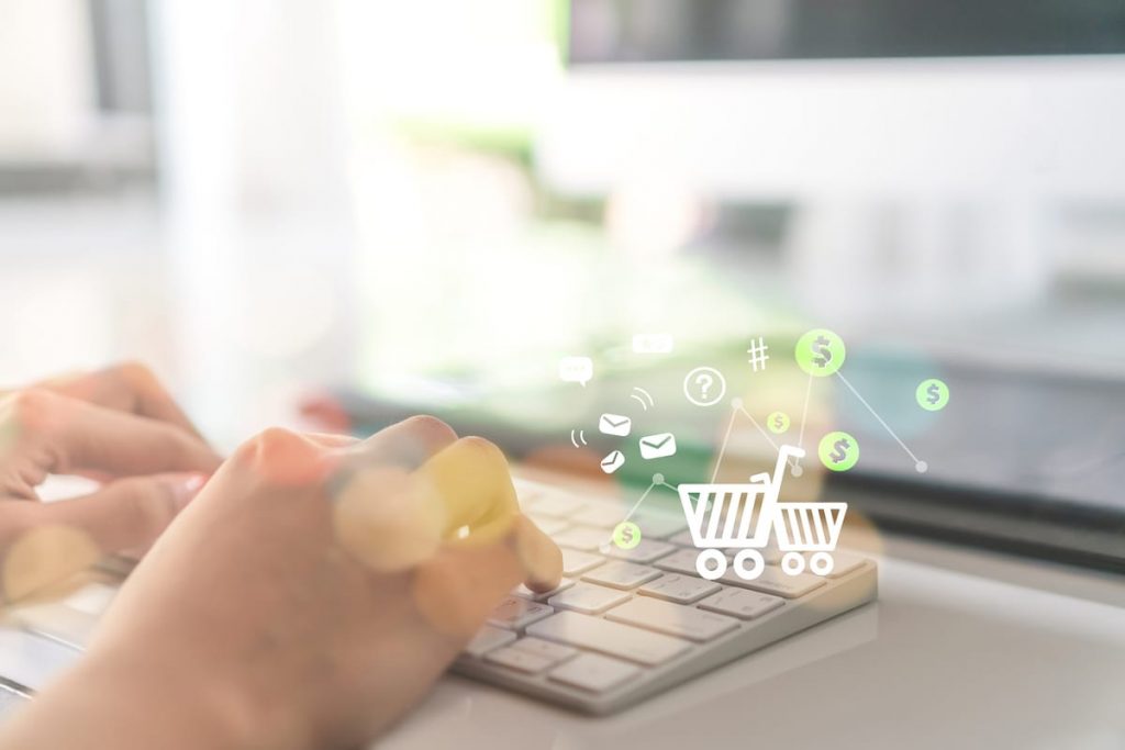Finanzas y Compras Online InteligenteFinanzas y Compras Online Inteligente Primer plano de manos tecleando con iconos de compras online y dinero, representando el control de gastos en las finanzas personales.