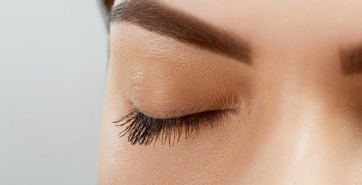 Mujer latina aplicando base de maquillaje con brocha frente al espejo