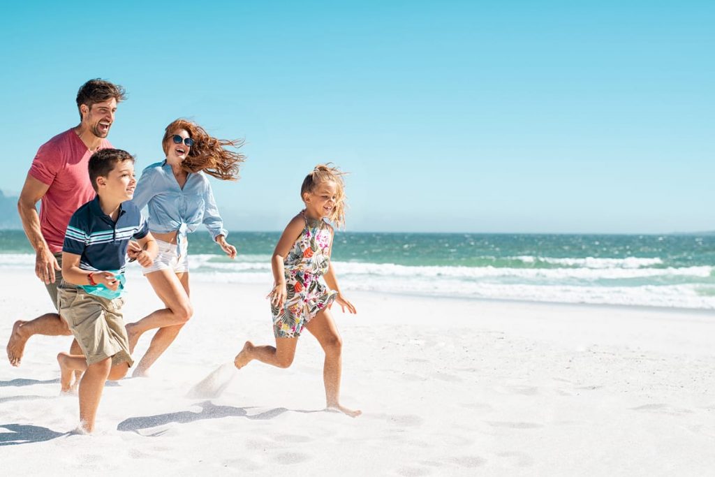 familia corriendo por la playa feliz en vacaciones