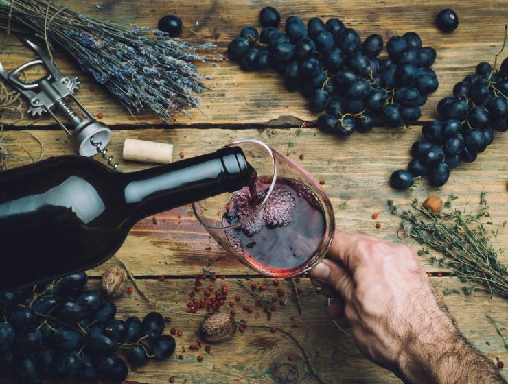 Día del Vino Argentino: una fiesta que se renueva con grandes noticias 6 Copa de vino tinto servida con uvas frescas y hierbas sobre mesa rústica