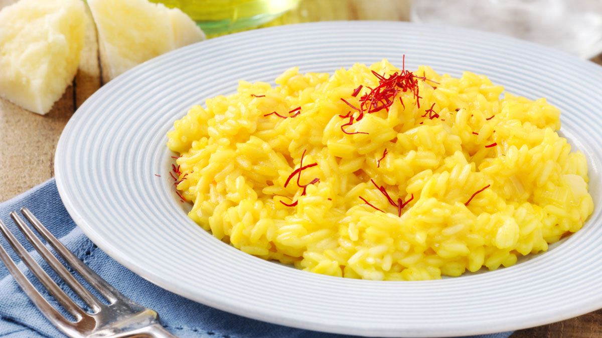 Plato de cremoso risotto a la milanesa, un arroz italiano de color amarillo por el azafrán, servido con queso parmesano.