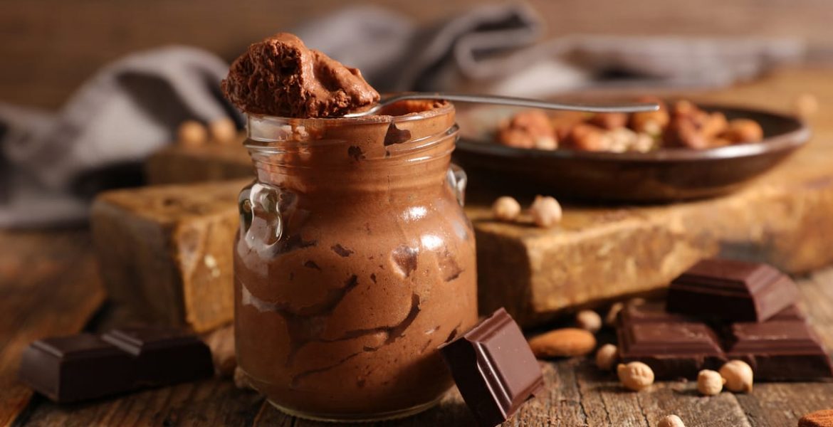 recipiente con mousse de chocolate y varios trozos de chocolate y frutos secos