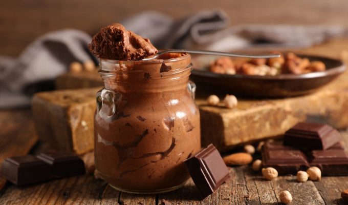 recipiente con mousse de chocolate y varios trozos de chocolate y frutos secos