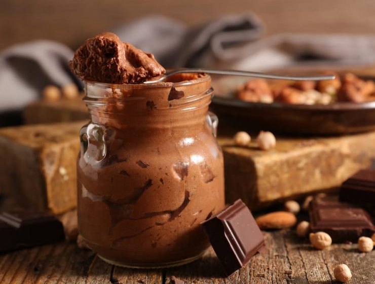 recipiente con mousse de chocolate y varios trozos de chocolate y frutos secos