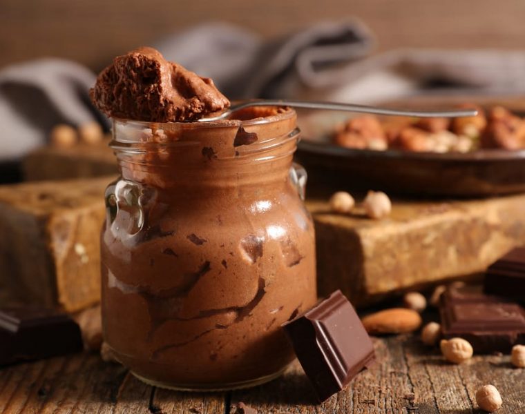 recipiente con mousse de chocolate y varios trozos de chocolate y frutos secos